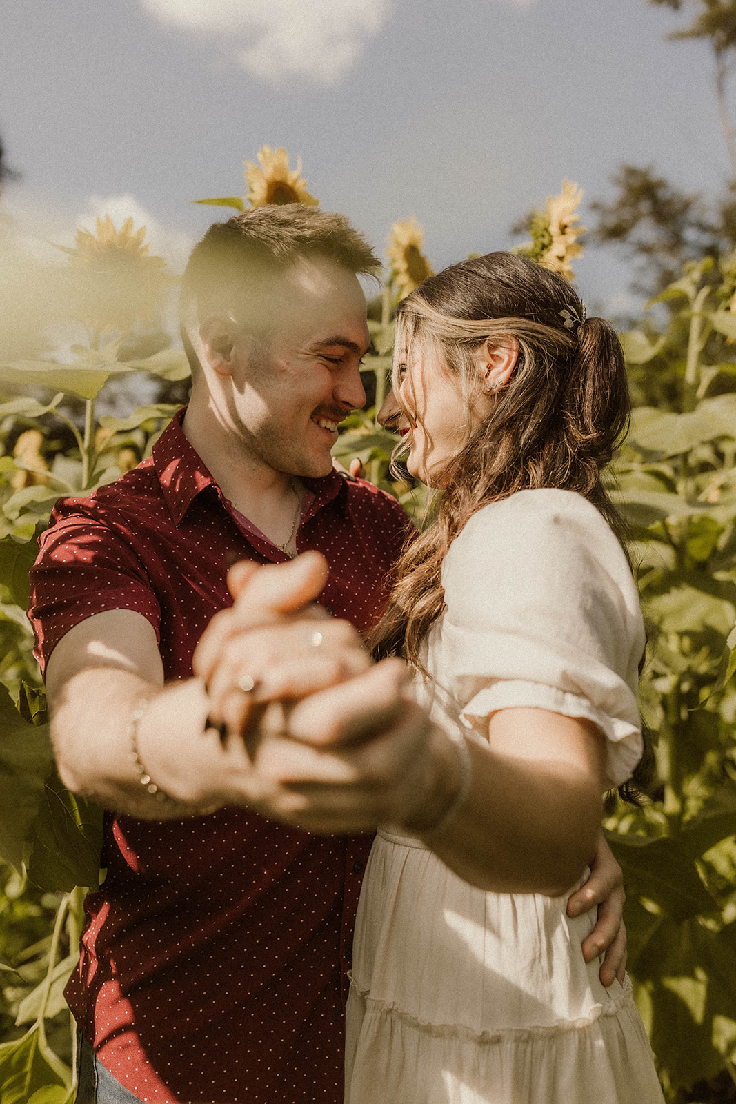 Couple holding hands in sunflower field.