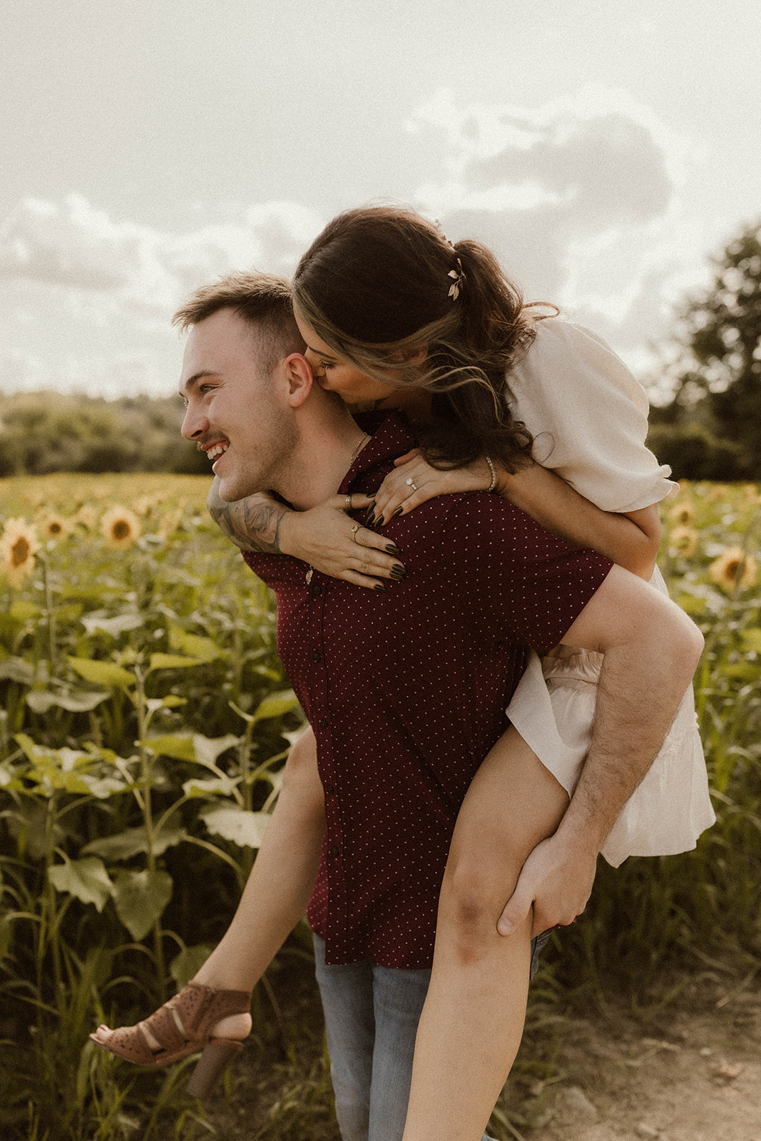 Man giving a lady a piggyback ride in a dreamy sunflower field.