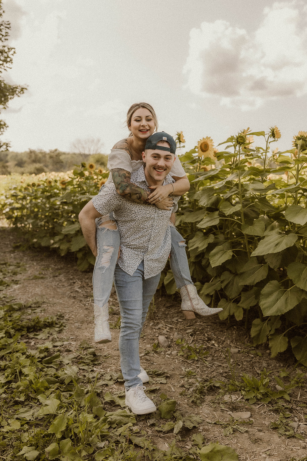Fun and playful engagement photos in a sunflower field filled with adventurous moments
