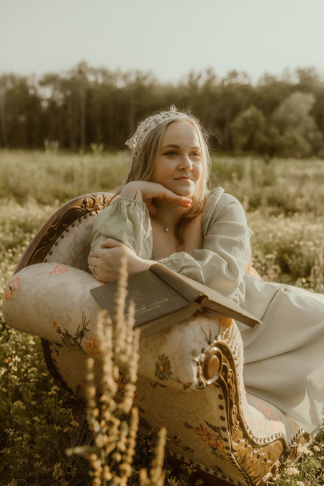young girl poses with a vintage chaise and tiara for creative self portraits in a field