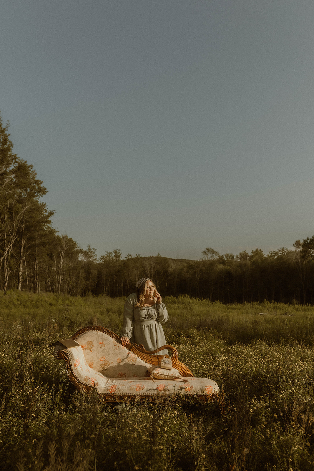 young girl poses with a vintage chaise during her field photoshoot