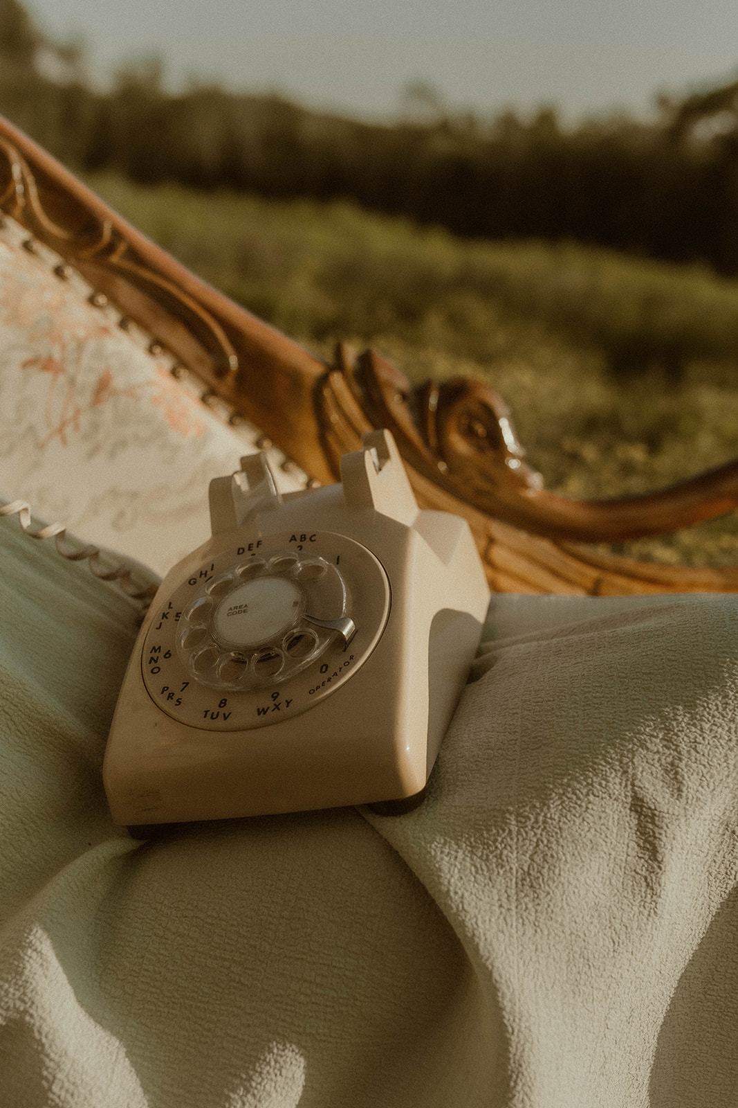 Detail photo of a rotary phone and vintage chaise used during a photoshoot in a wildflower field