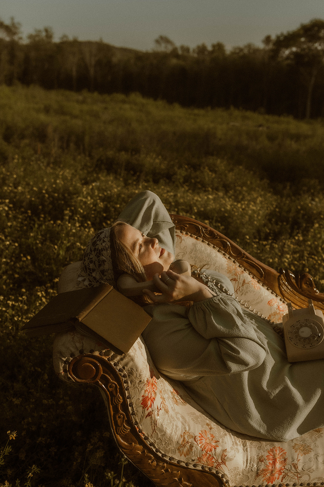 young girl poses with a vintage chaise for creative self portraits in a field