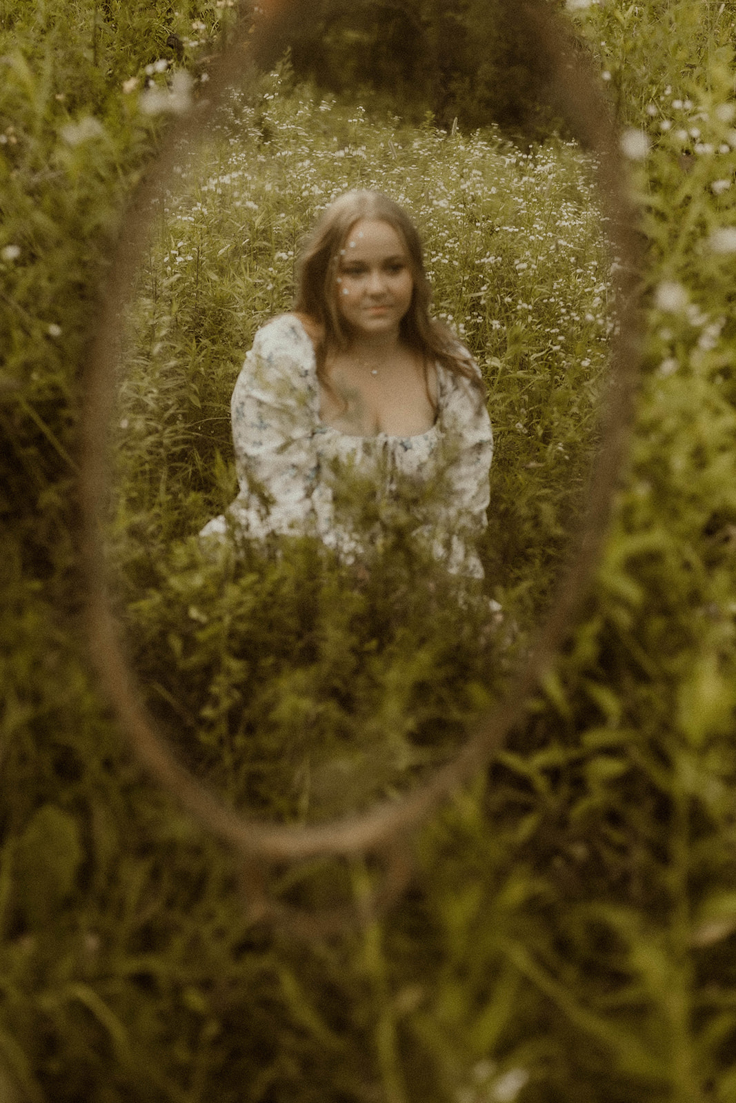 stunning young lady takes creative self portraits with a mirror in a wildflower field