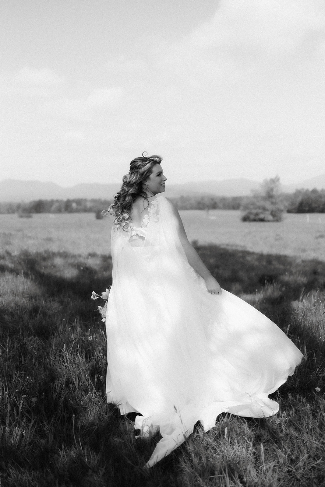 Beautiful bride takes a candid walking photo in front of the beautiful backdrop of the Adirondack mountain
