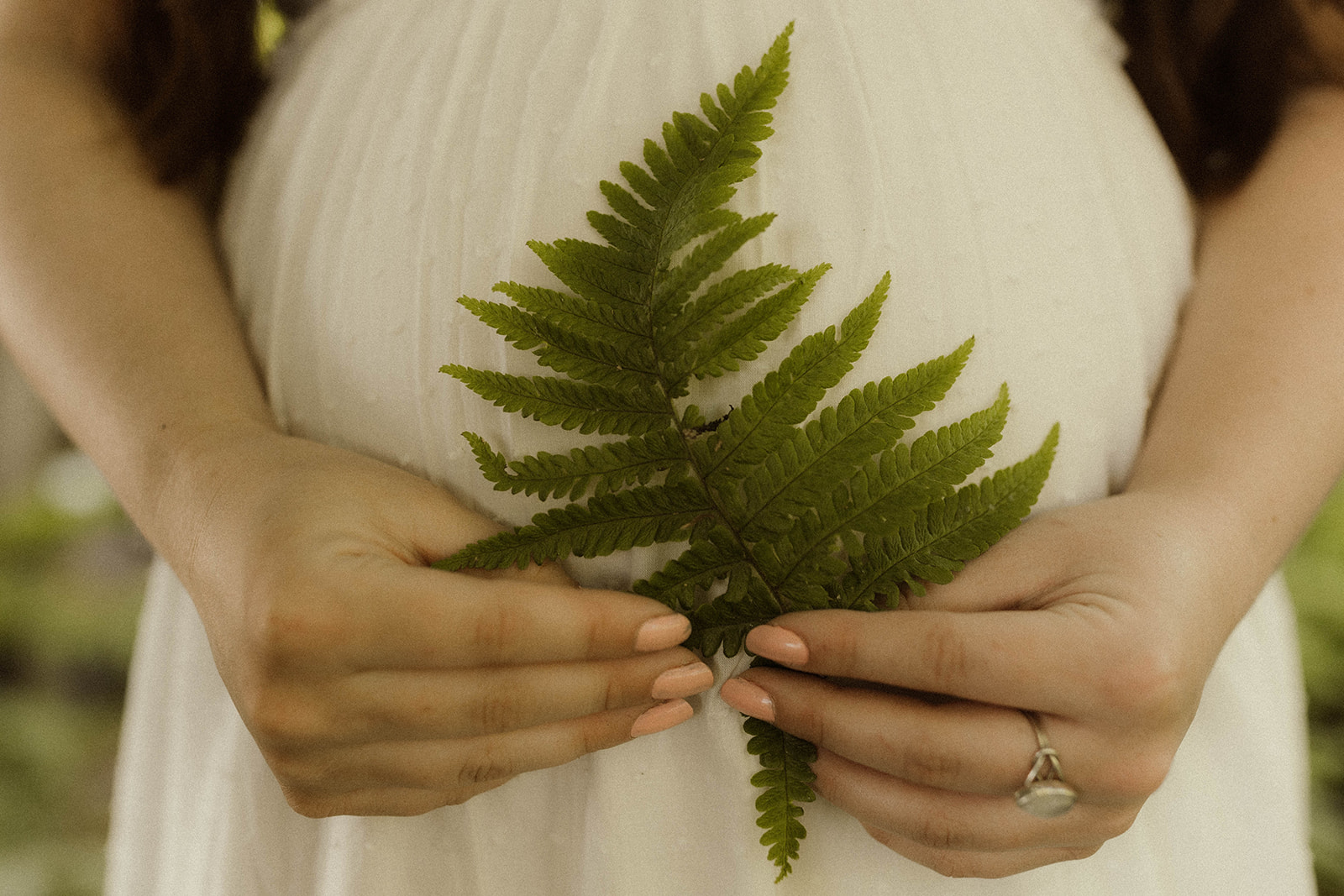 Elegant soon to be mom poses with a fern during her unique maternity photoshoot