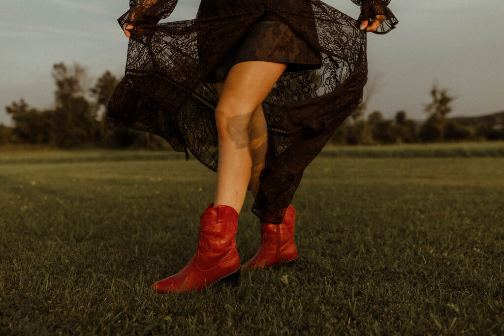 western woman wearing red cowgirl boots in wild flower field.