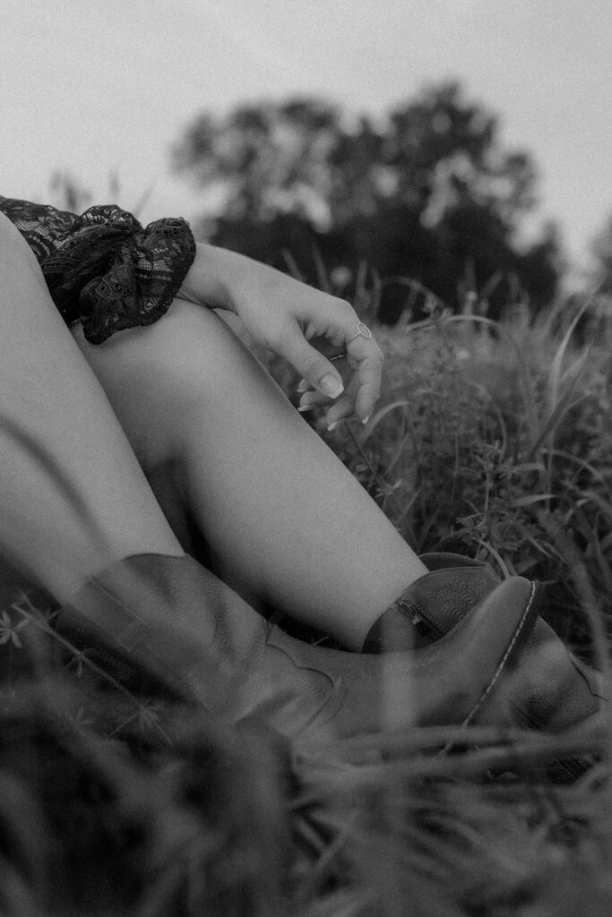 black and white photo with cowgirl boots on in wildflower field.