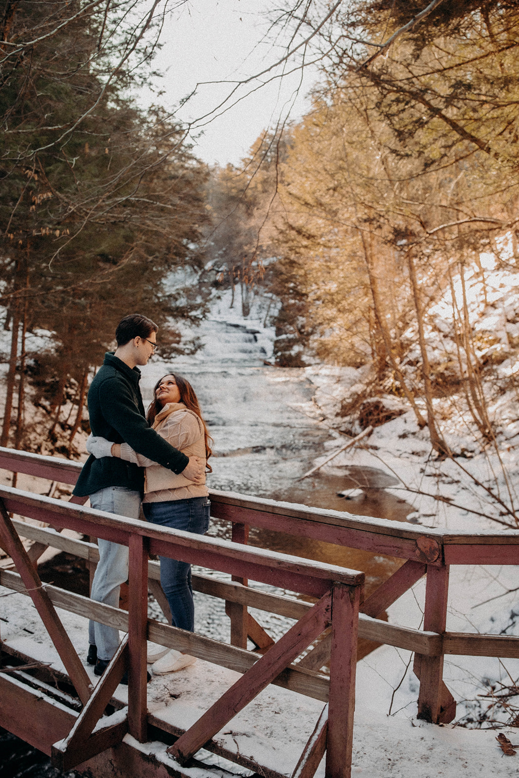 Candid photo of a couple walking on a snow covered bridge in Huyck preserve in Rensselaerville New York!