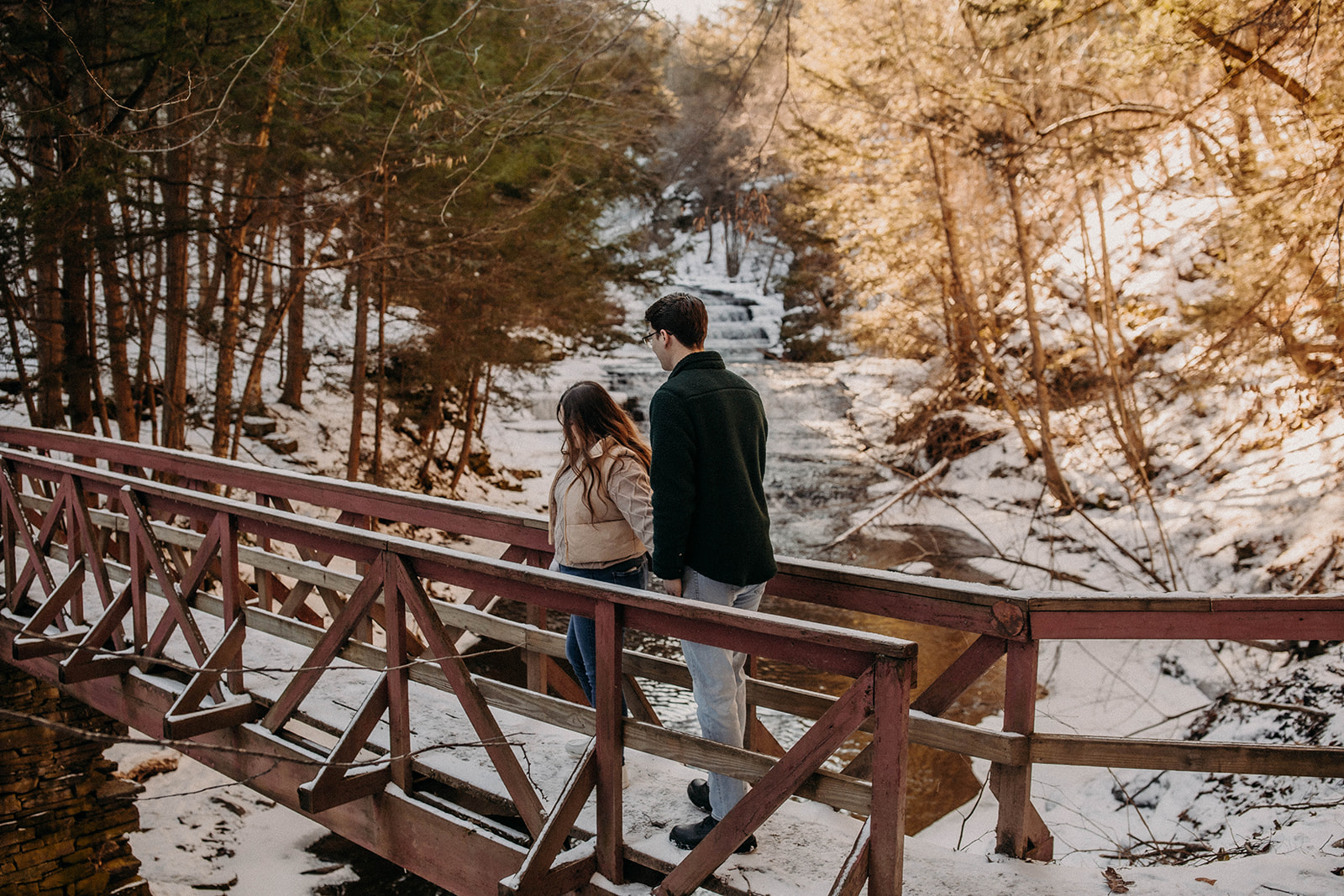 Candid photo of a couple walking on a snow covered bridge in Huyck preserve in Rensselaerville New York!