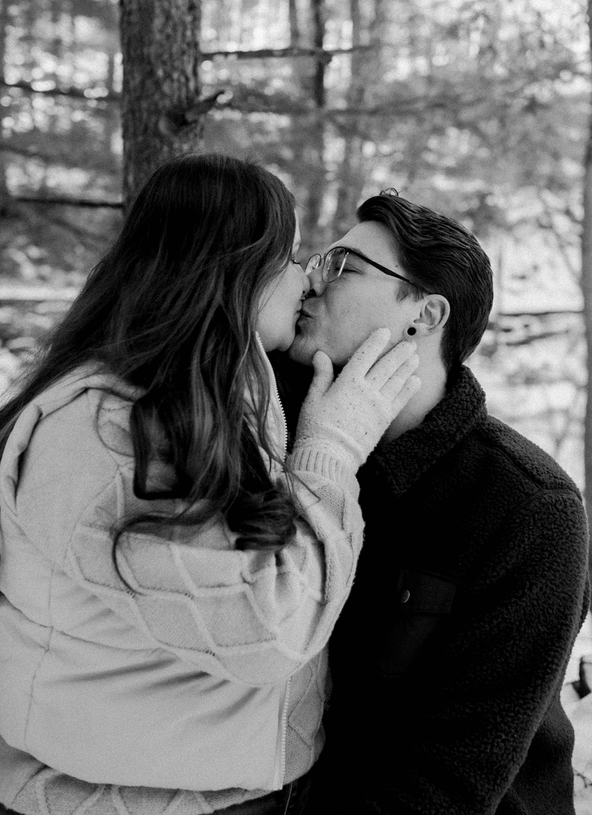 Beautiful couple share a kiss during their snowy winter engagement photoshoot!