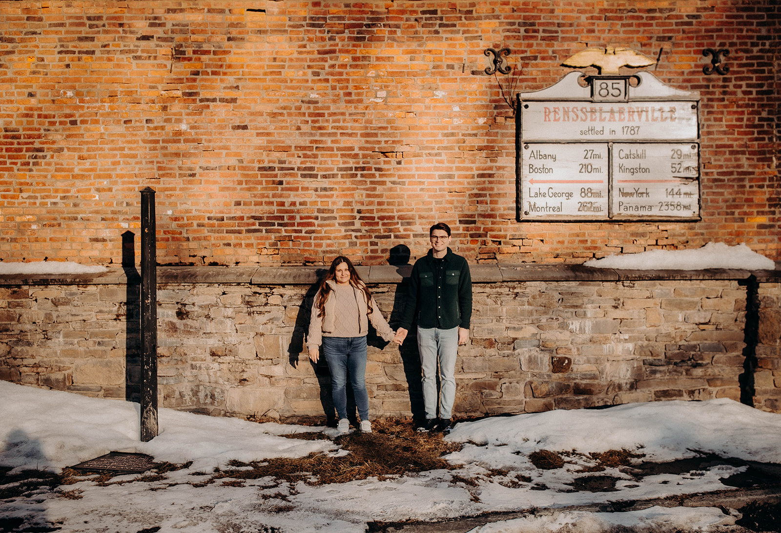 Couple pose together outside a historic Rensselaerville New York building during their dreamy winter engagement photoshoot
