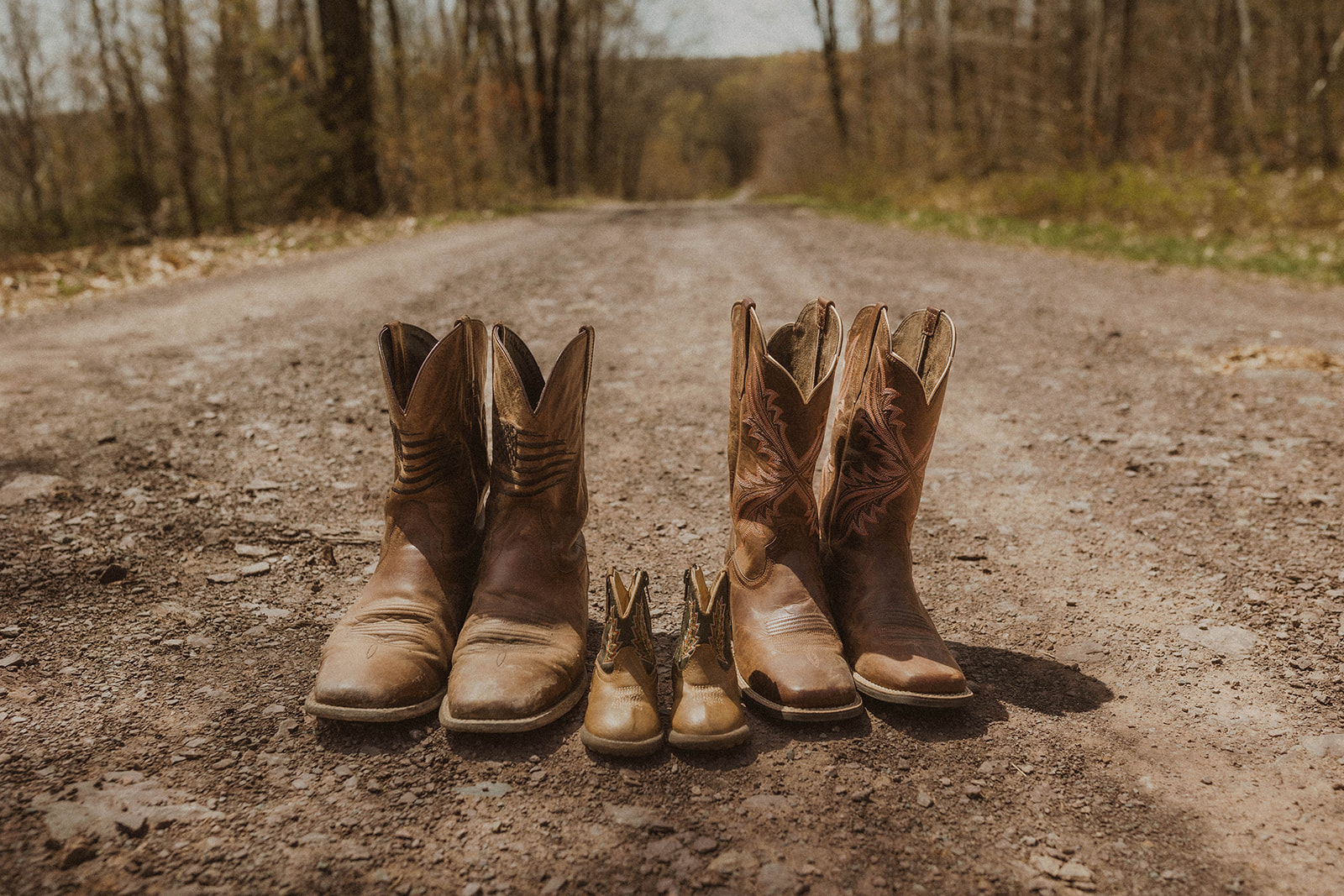 Mom, dad and sons boots lined up on a road during their dreamy upstate New York western maternity shoot