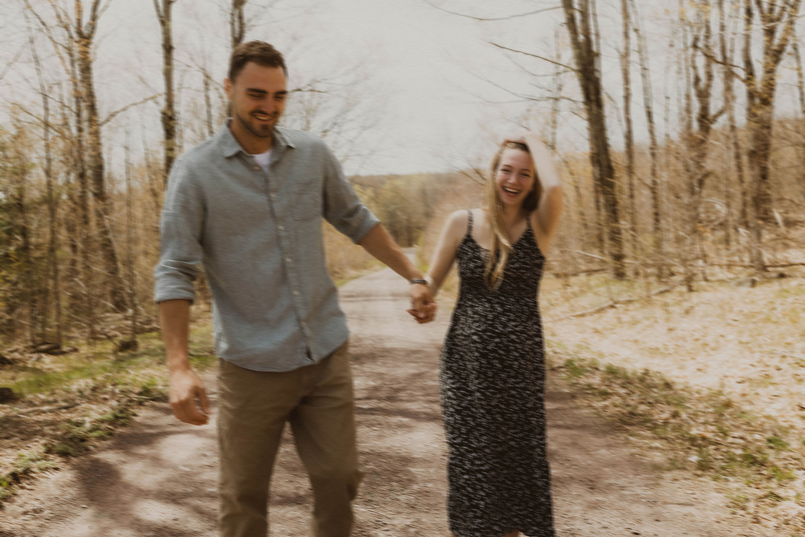 Stunning future mom and dad walk together and share laughter on a country road
