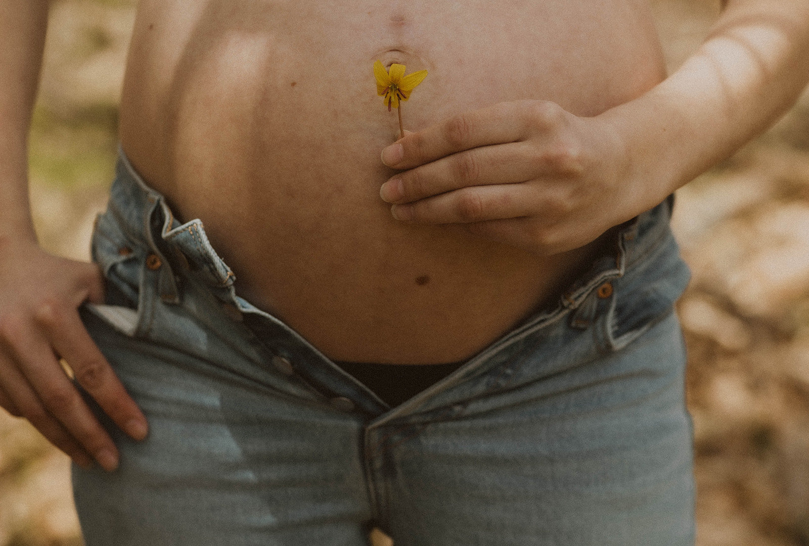 A detail shot of the future moms tummy and a yellow wild flower