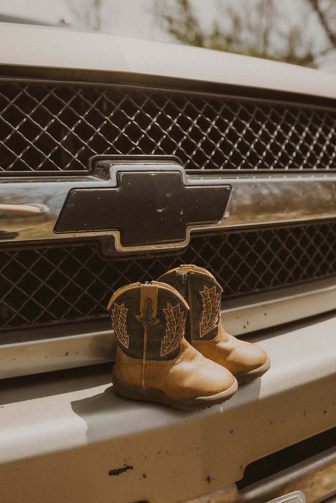 A couples future sons boot on their Chevy truck grill during their western maternity photos