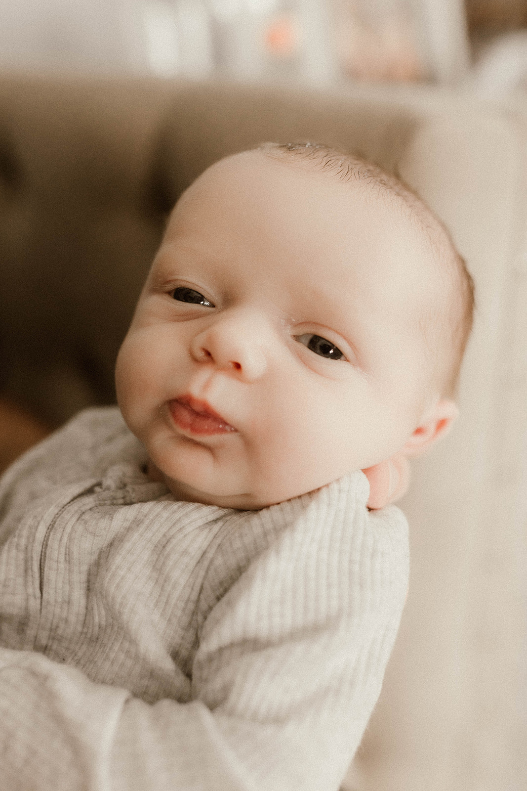 Little man poses for the camera duing this in home newborn photography session
