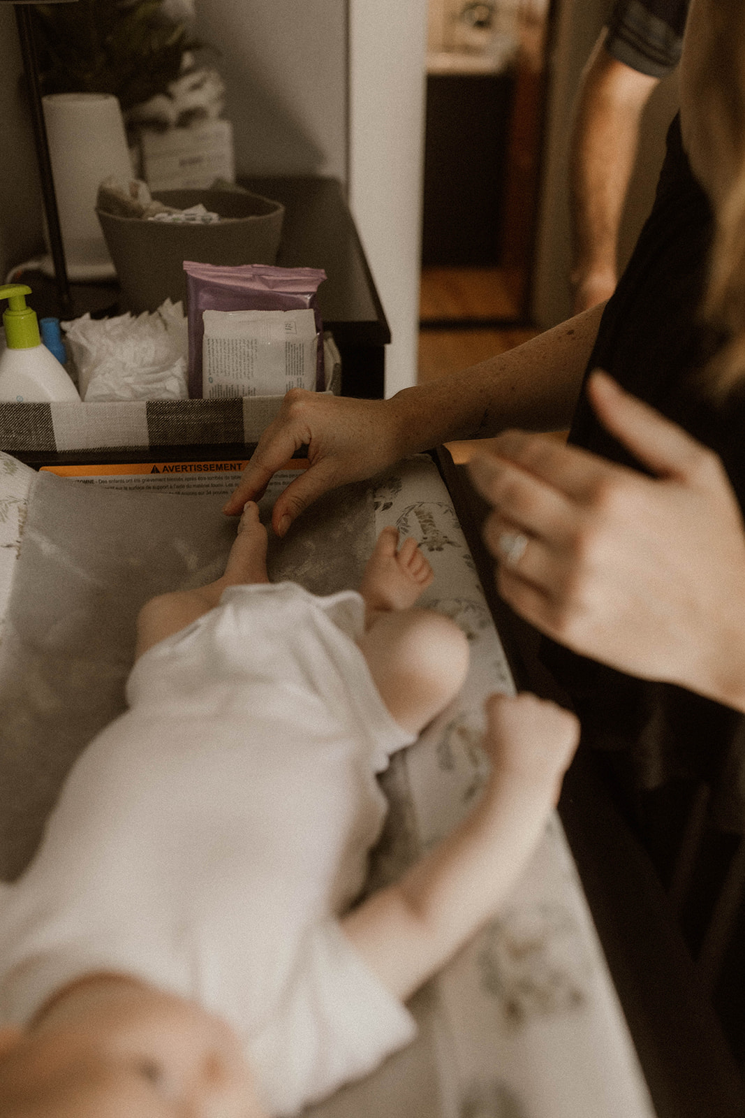 A new mom plays with her sons tiny feet during their intimate in home newborn photo session