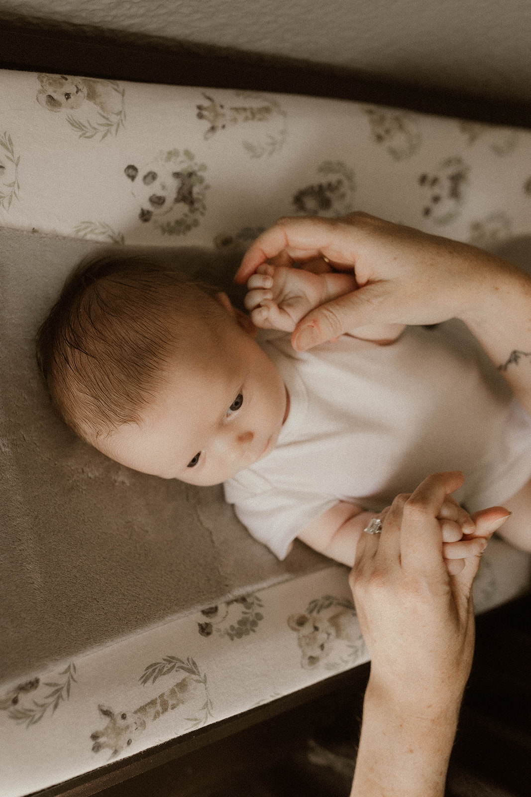 A new mom plays with her sons tiny hands during their intimate in home newborn photo session