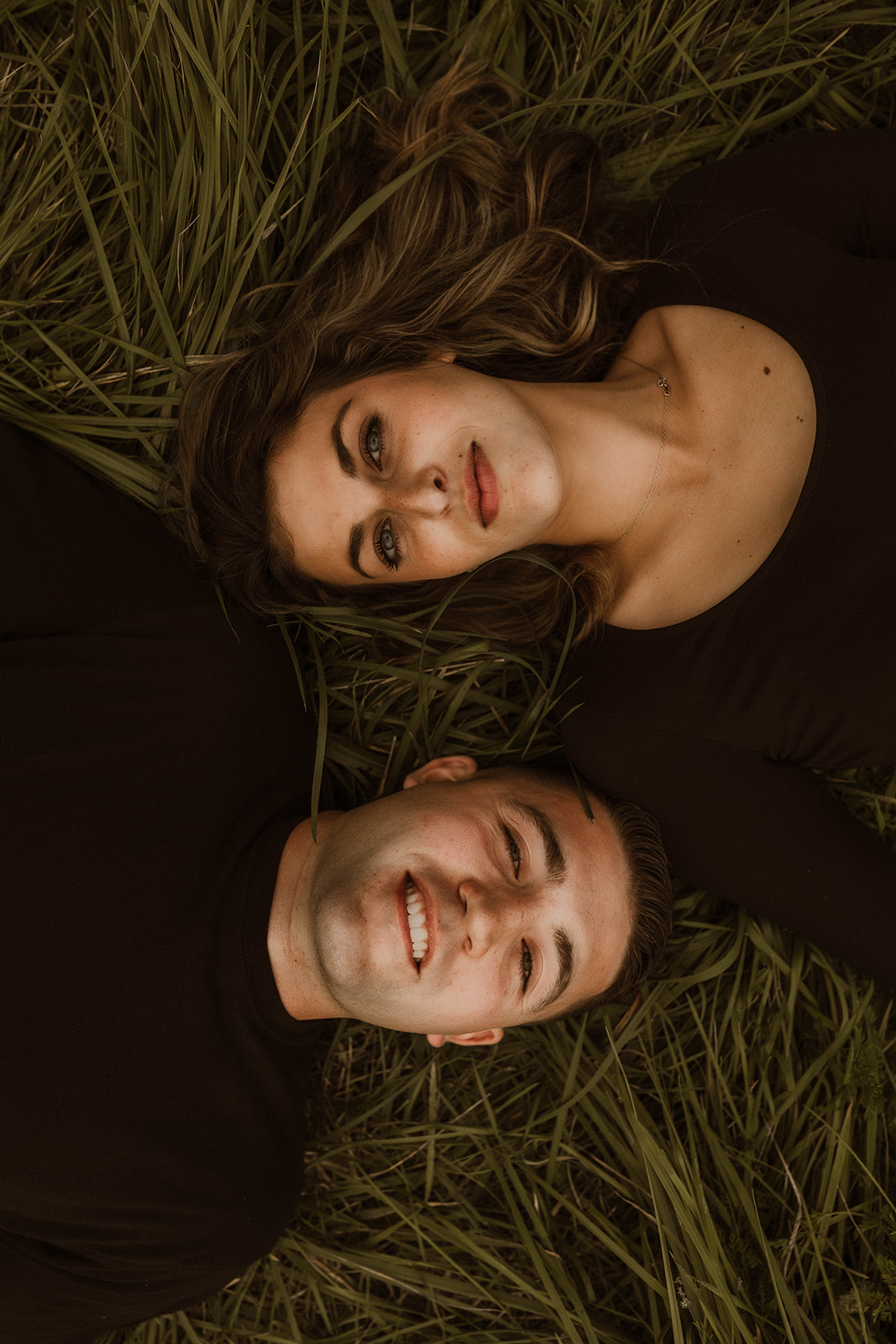 Beautiful couple pose together laying in a wildflower field 