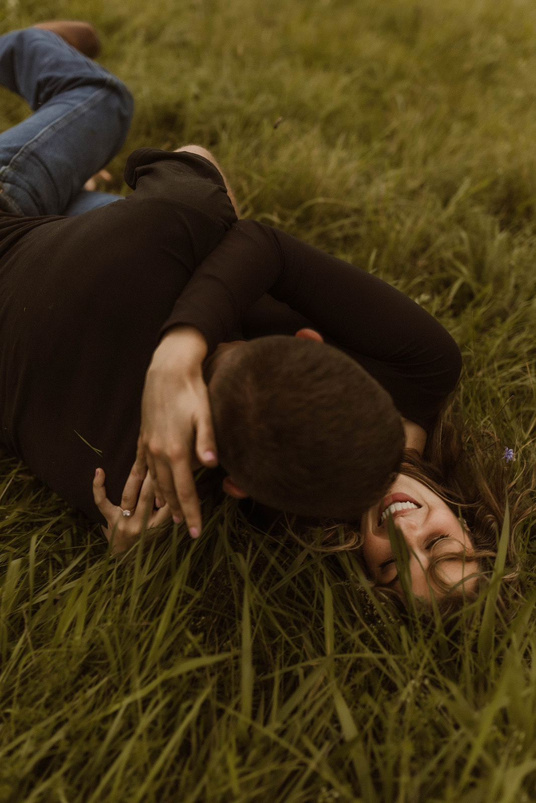 Beautiful couple pose together laying in a wildflower field 