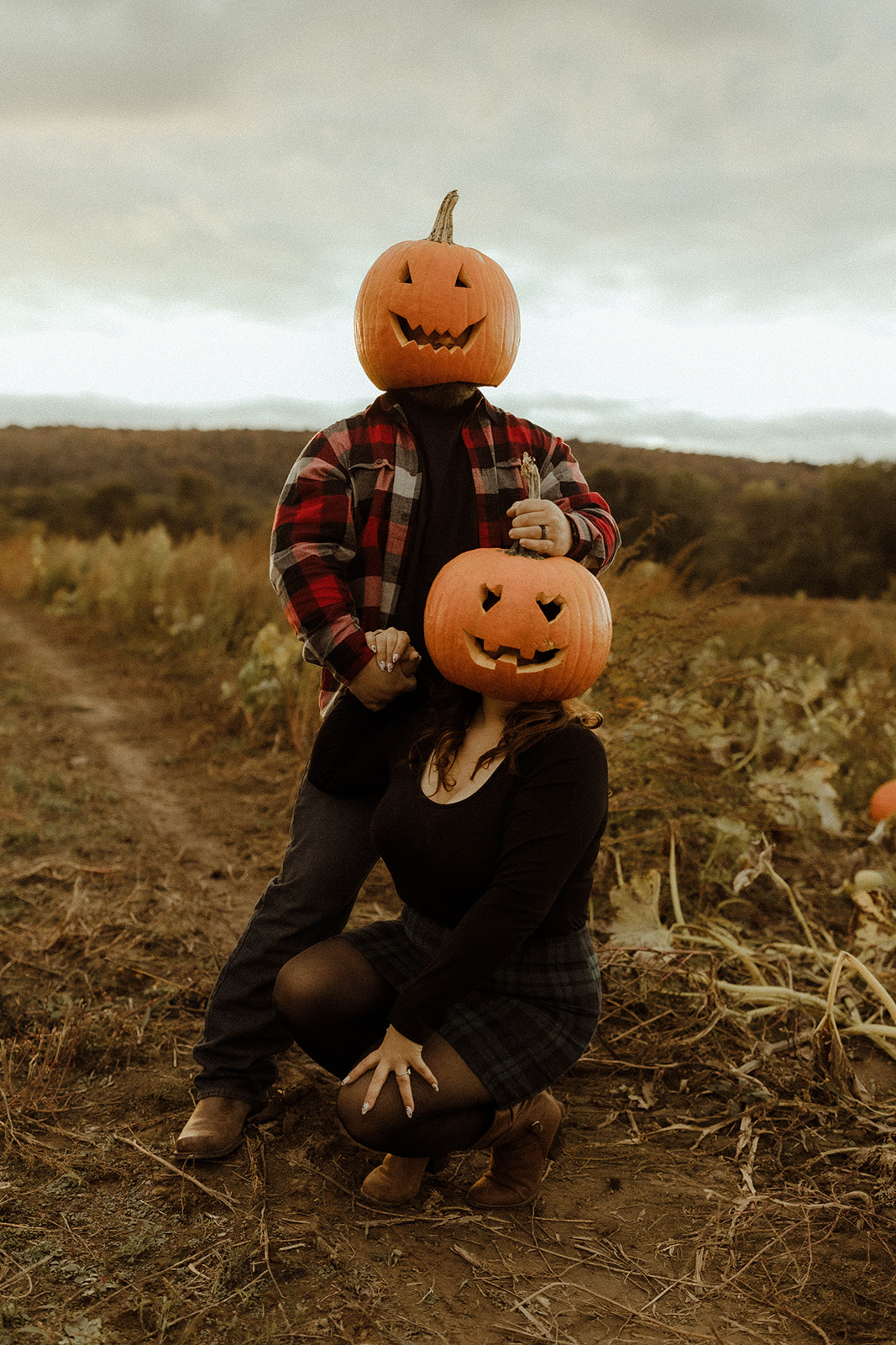 Beautiful couple pose with pumpkinheads during their upstate New York engagement photos
