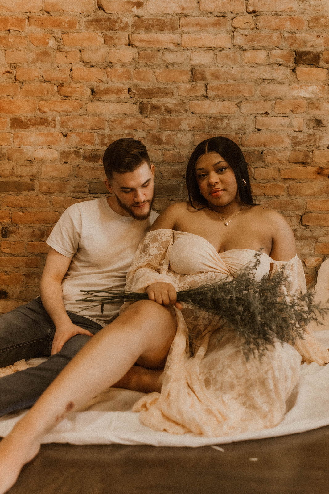Couple sitting indoor for maternity session with flowers.