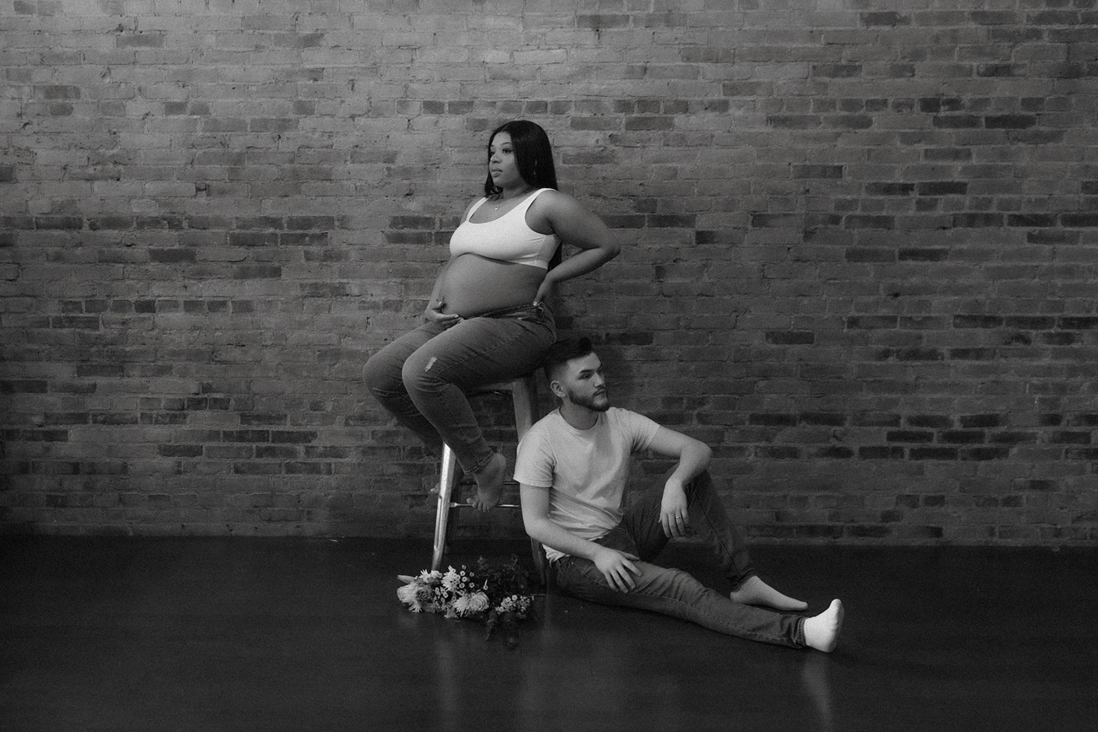 Couple during maternity session sitting pose with flowers