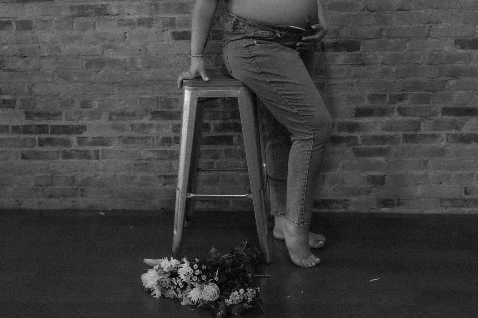 Sitting maternity session pose indoors with flowers